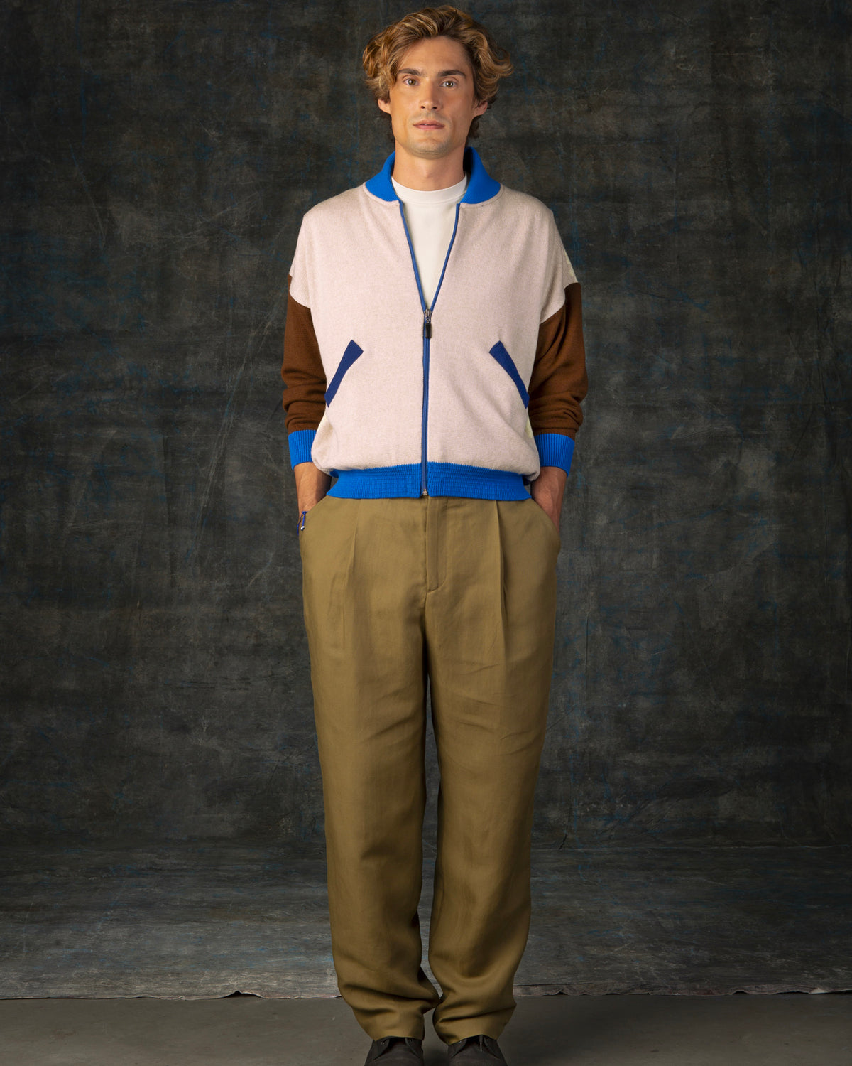 Male model wearing an ecru and brown zip-up bomber jacket with cobalt blue details.
