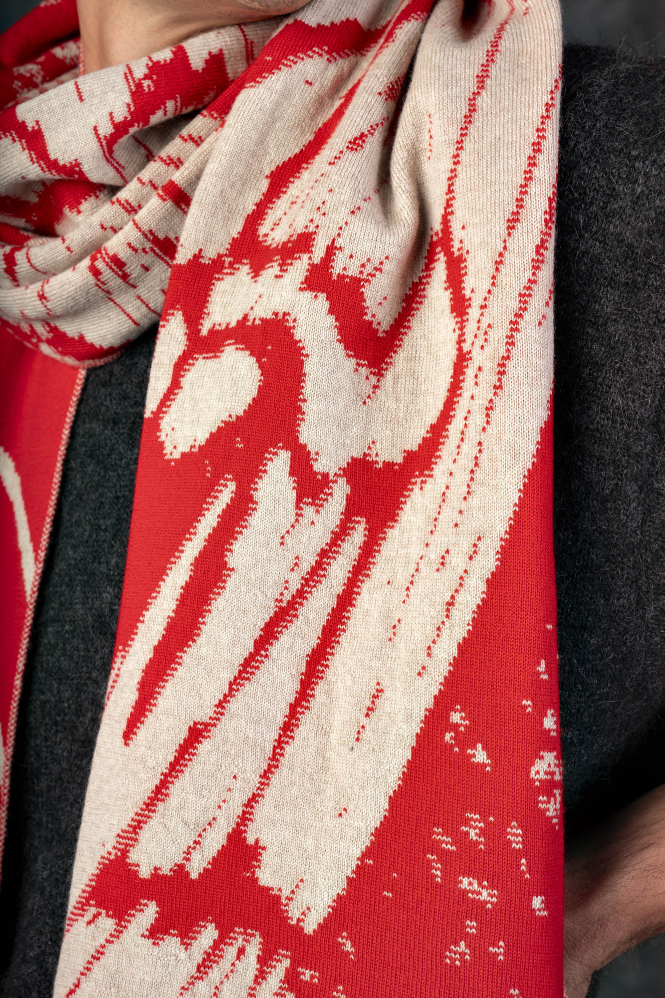 Close-up of a bright red and beige scarf with a nature-inspired pattern.