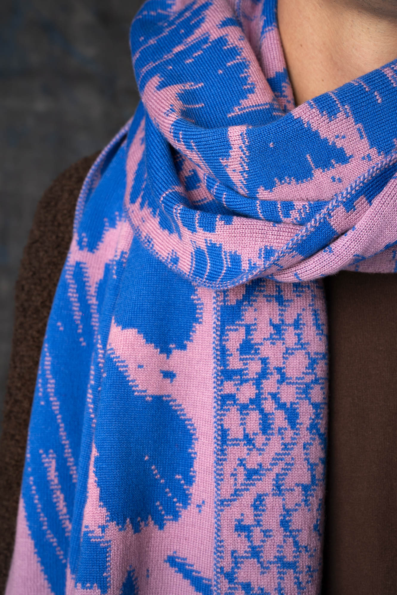 Close-up of a cobalt blue and pink patterned scarf draped around a model's neck.