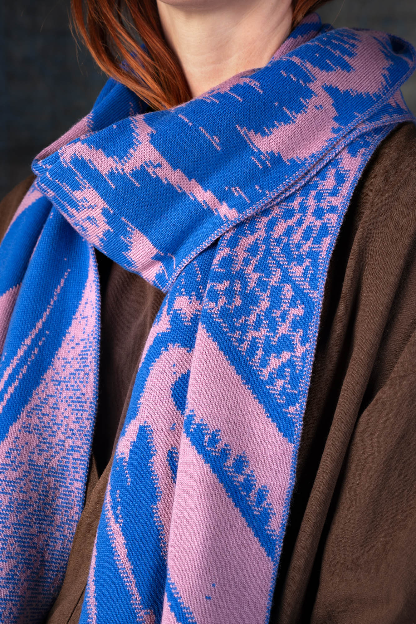 Close-up of a cobalt blue and pink patterned scarf being worn around the neck.