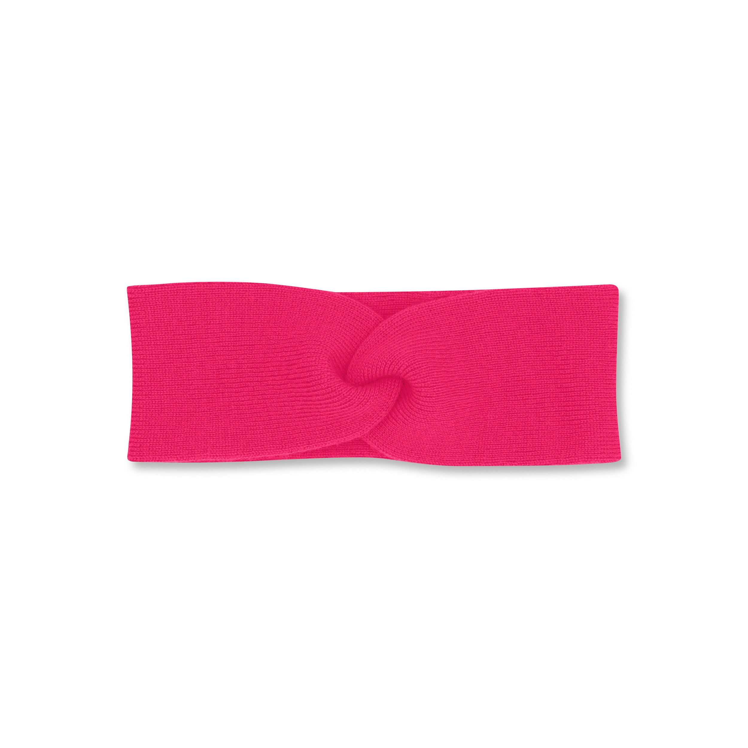 Product photo of a twisted bright pink headband, set against a plain background.