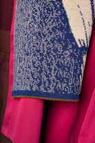 Close-up of a dark blue and beige scarf with cacao brown detail at the end.