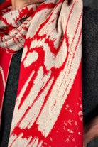 Close-up of a bright red and beige scarf with a nature-inspired pattern.