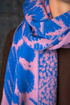 Close-up of a cobalt blue and pink patterned scarf draped around a model's neck.